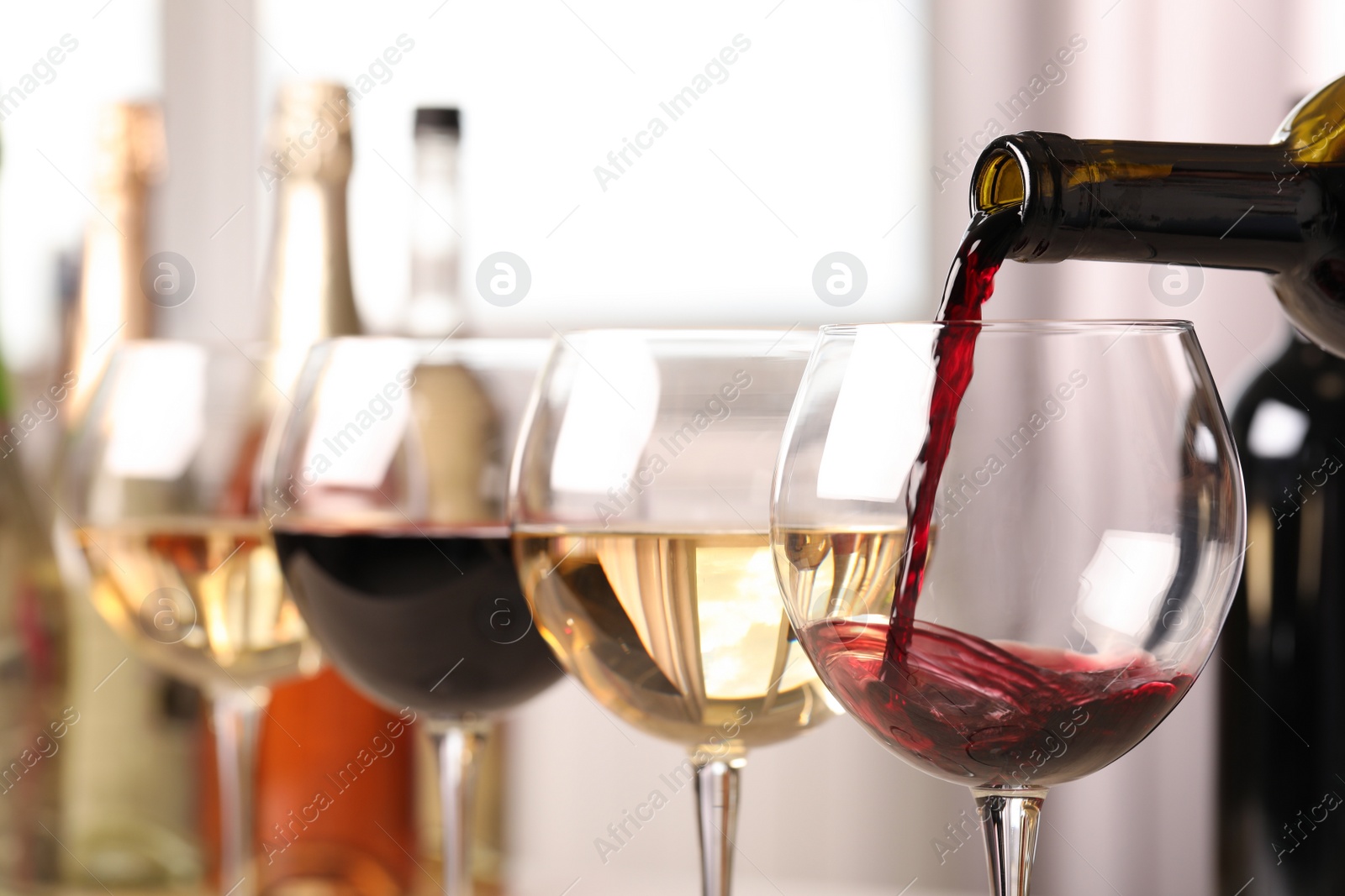 Photo of Pouring red wine from bottle into glass, closeup