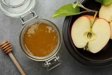 Photo of Sweet honey and fresh apple on grey table, flat lay