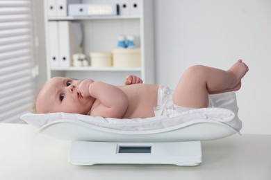 Photo of Cute little baby lying on scales in clinic