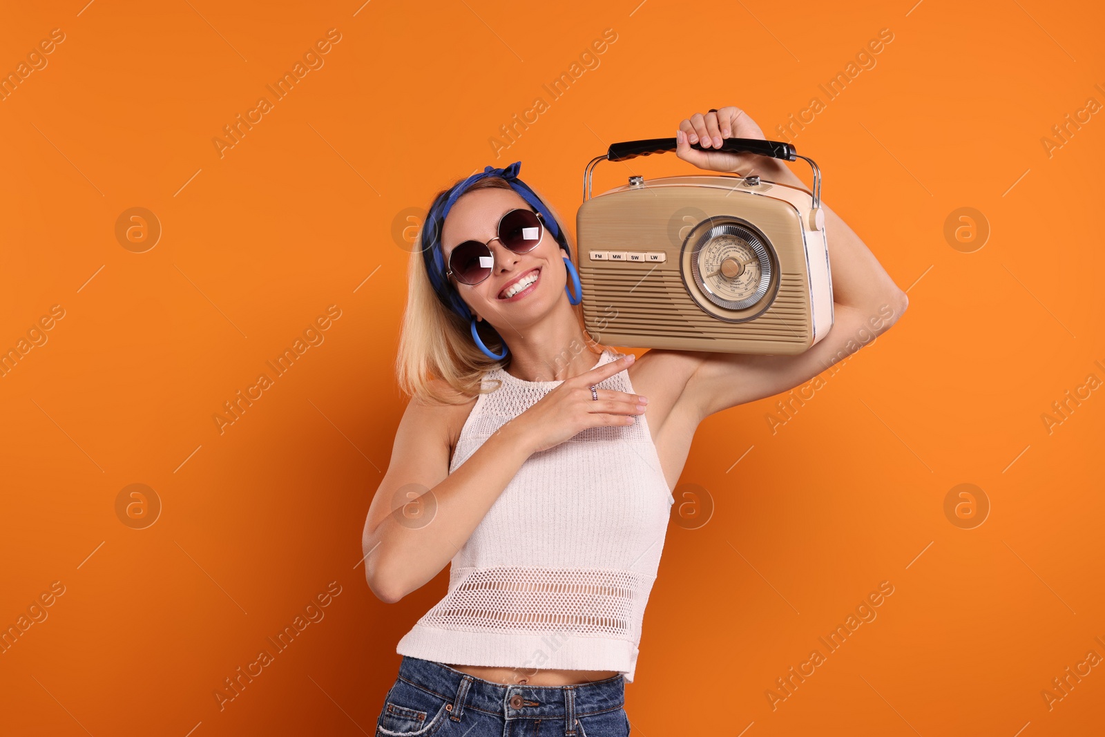 Photo of Happy hippie woman with retro radio receiver on orange background