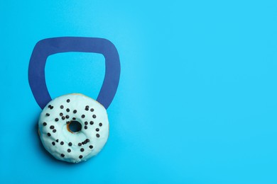 Photo of Kettlebell made of tasty doughnut on light blue background, top view. Space for text