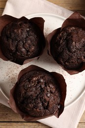 Tasty chocolate muffins on wooden table, top view