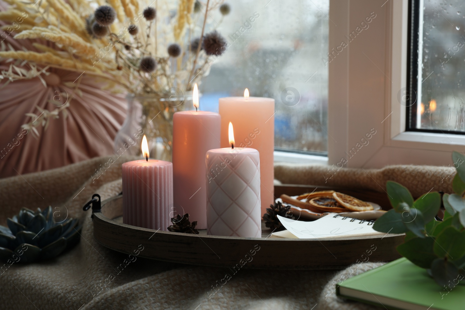 Photo of Tray with burning wax candles and decor on window sill indoors