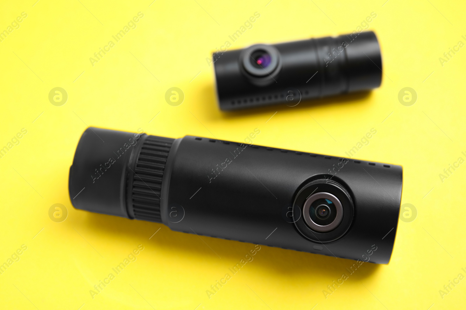 Photo of Black modern car cameras on yellow background, closeup