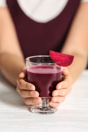 Woman with glass of beet smoothie at table, closeup