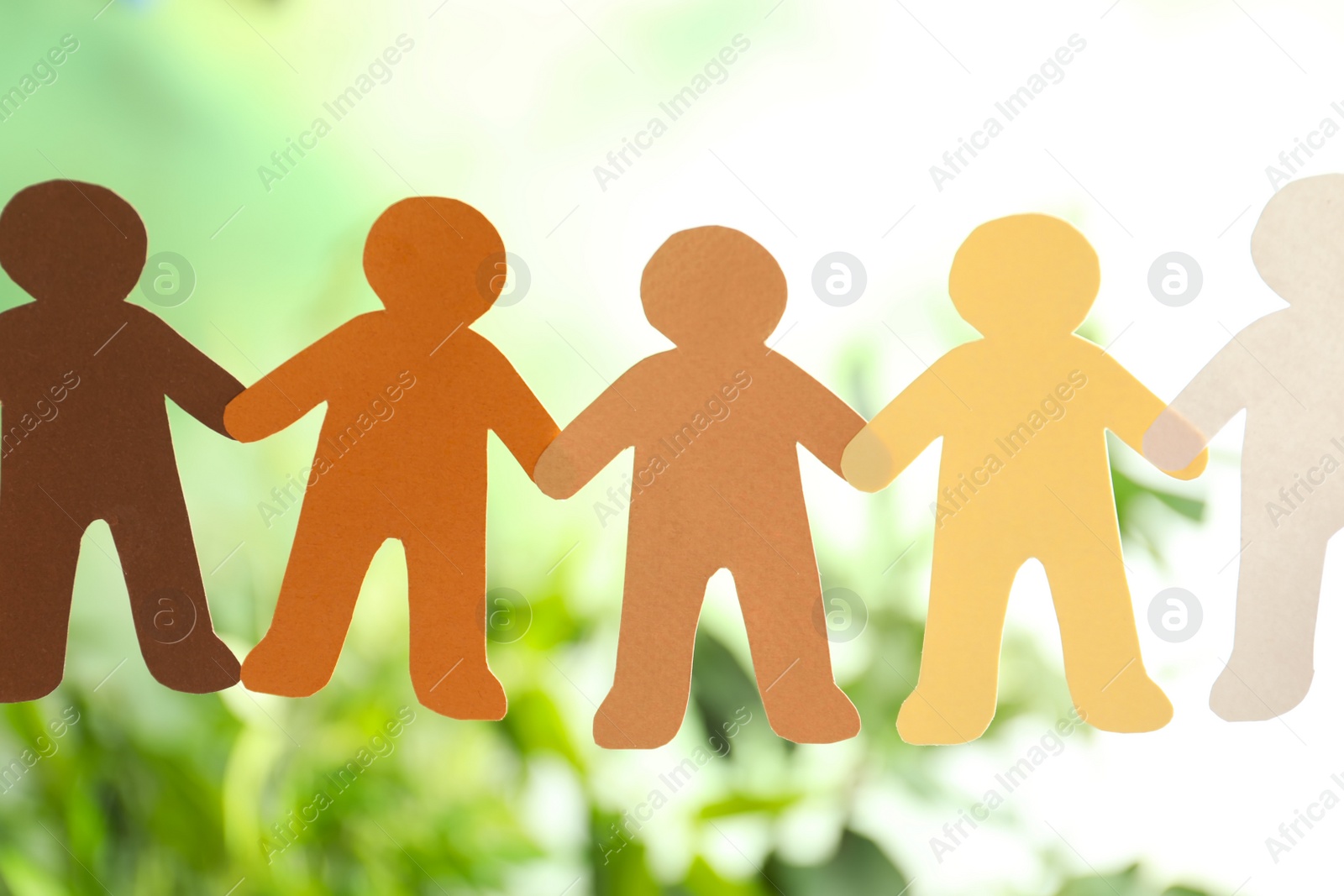 Photo of Paper people holding hands on blurred background. Unity concept