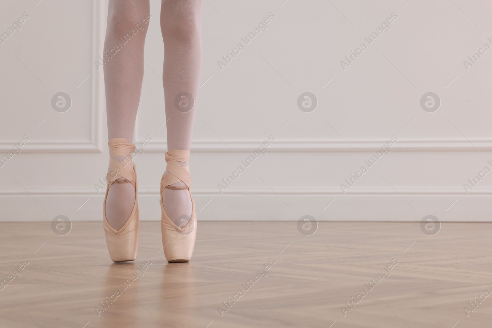 Photo of Little ballerina practicing dance moves in studio, closeup of legs. Space for text