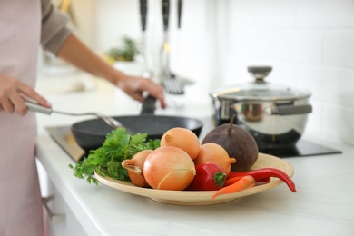 Photo of Plate with golden onions and vegetables in kitchen, closeup