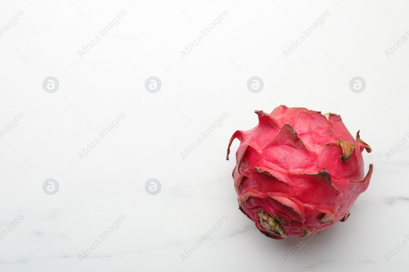 Photo of Delicious red pitahaya fruit on white marble table, top view. Space for text