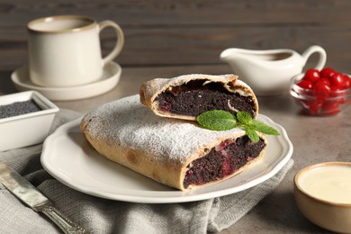 Delicious strudel with cherries and poppy seeds on grey table, closeup