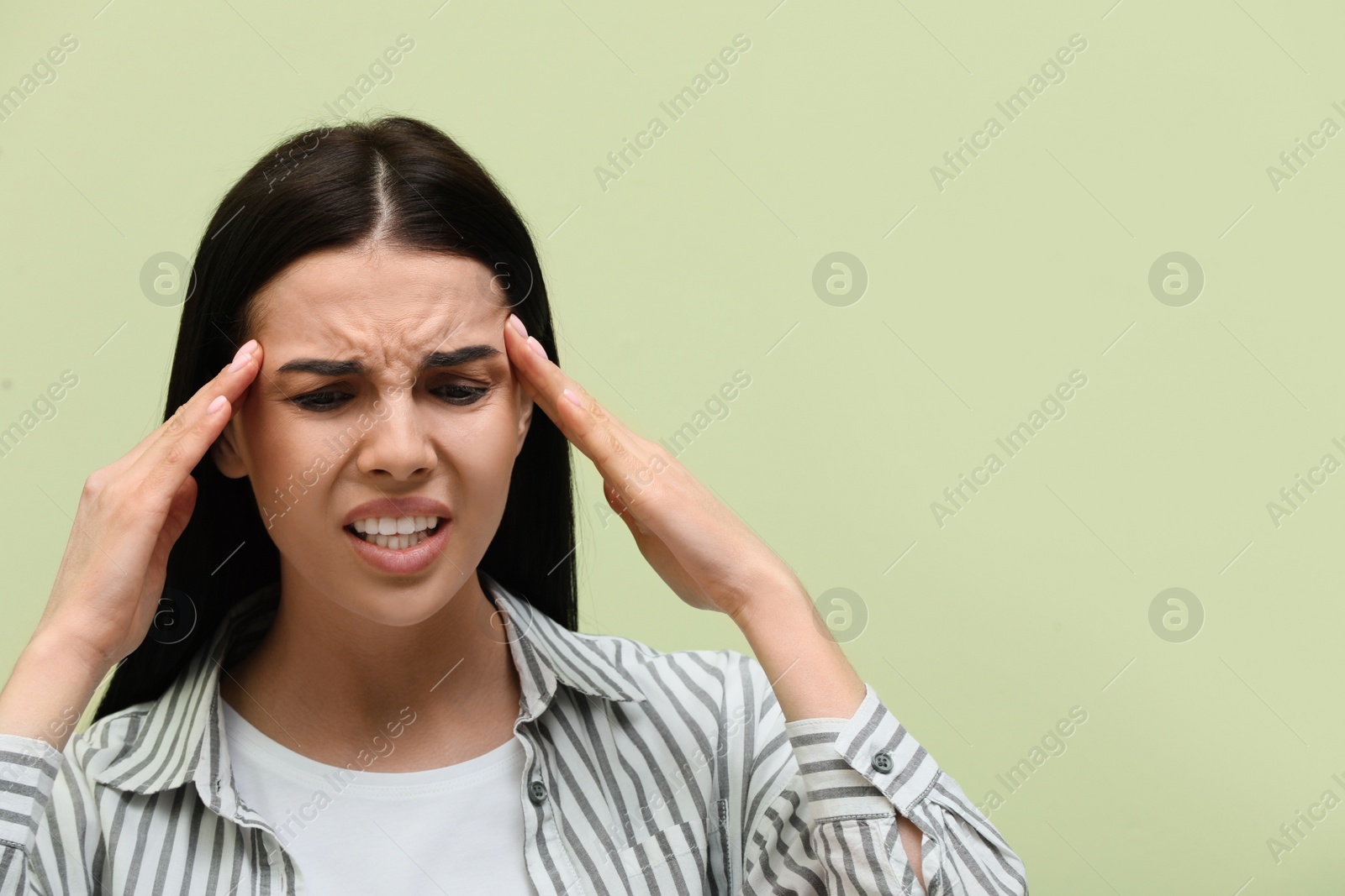 Photo of Woman suffering from migraine on light green background, space for text
