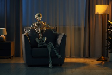 Waiting concept. Human skeleton sitting in armchair indoors, space for text