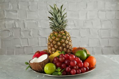 Photo of Plate with different ripe fruits on grey table