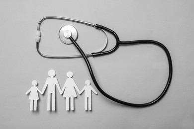 Photo of Paper family cutout and stethoscope on grey background, flat lay. Insurance concept