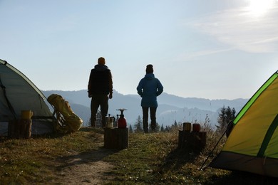 Photo of Couple enjoying beautiful mountain landscape near camping tents, back view