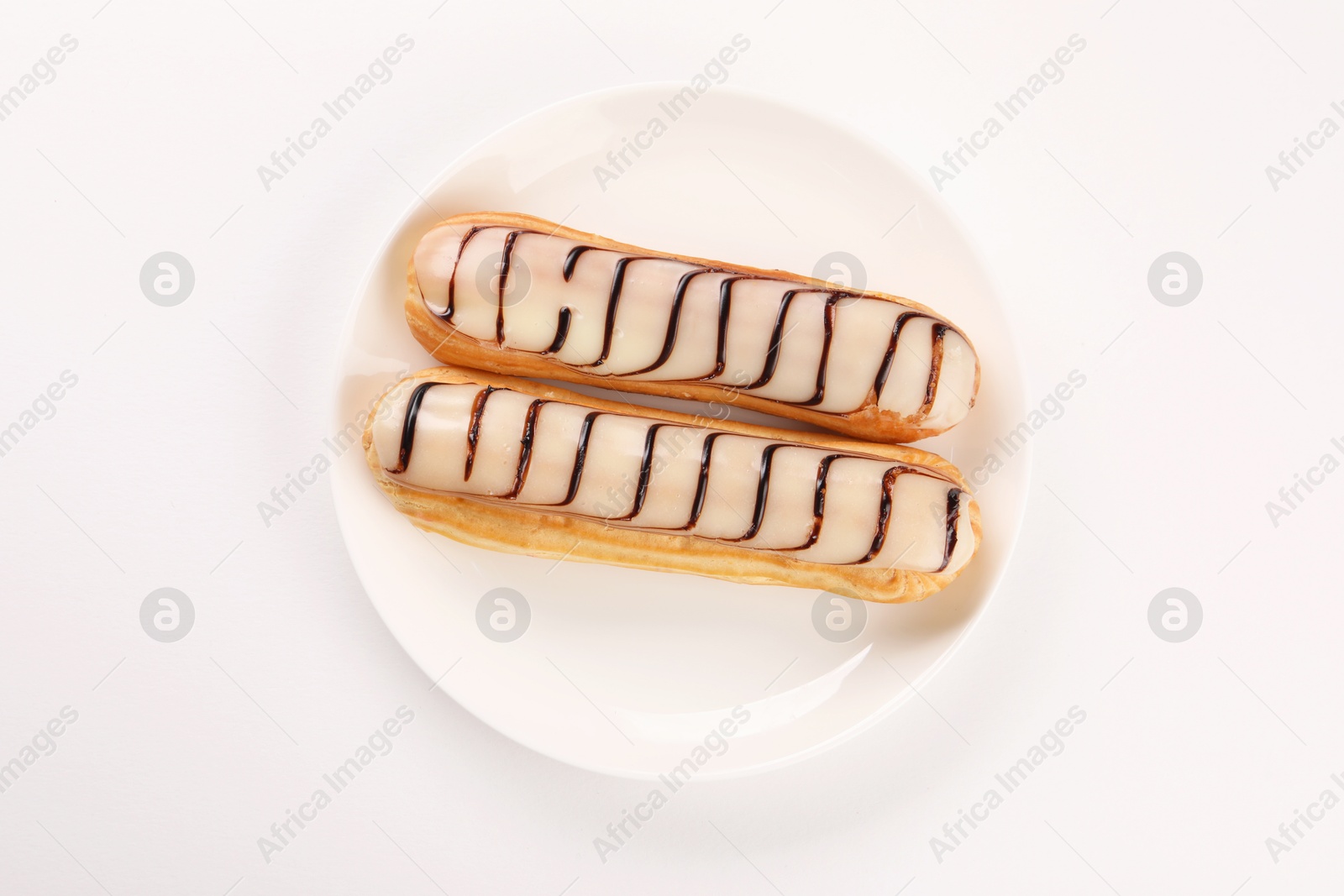 Photo of Delicious eclairs covered with glaze on white background, top view