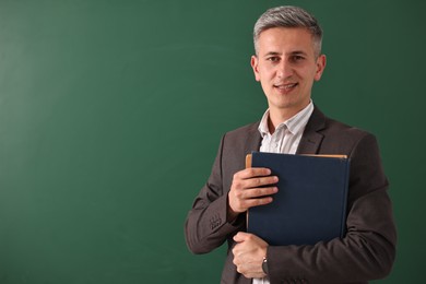 Teacher with notebooks near chalkboard, space for text