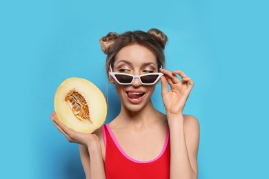 Photo of Young woman with fresh melon on light blue background. Exotic fruit