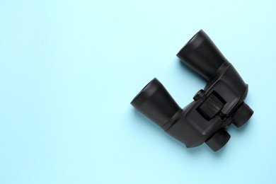 Modern binoculars on light blue background, top view. Space for text