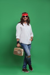 Photo of Stylish hippie man in sunglasses with retro radio receiver on green background