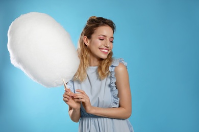 Portrait of pretty young woman with cotton candy on blue background