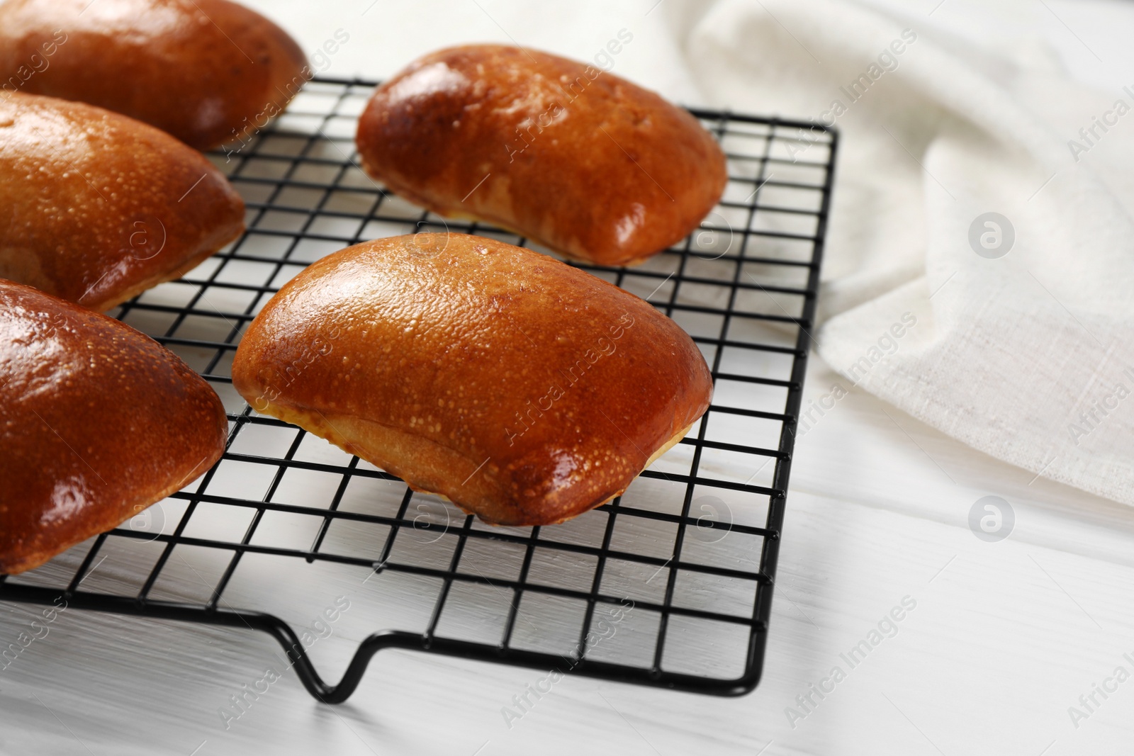 Photo of Delicious baked pirozhki on white wooden table, closeup