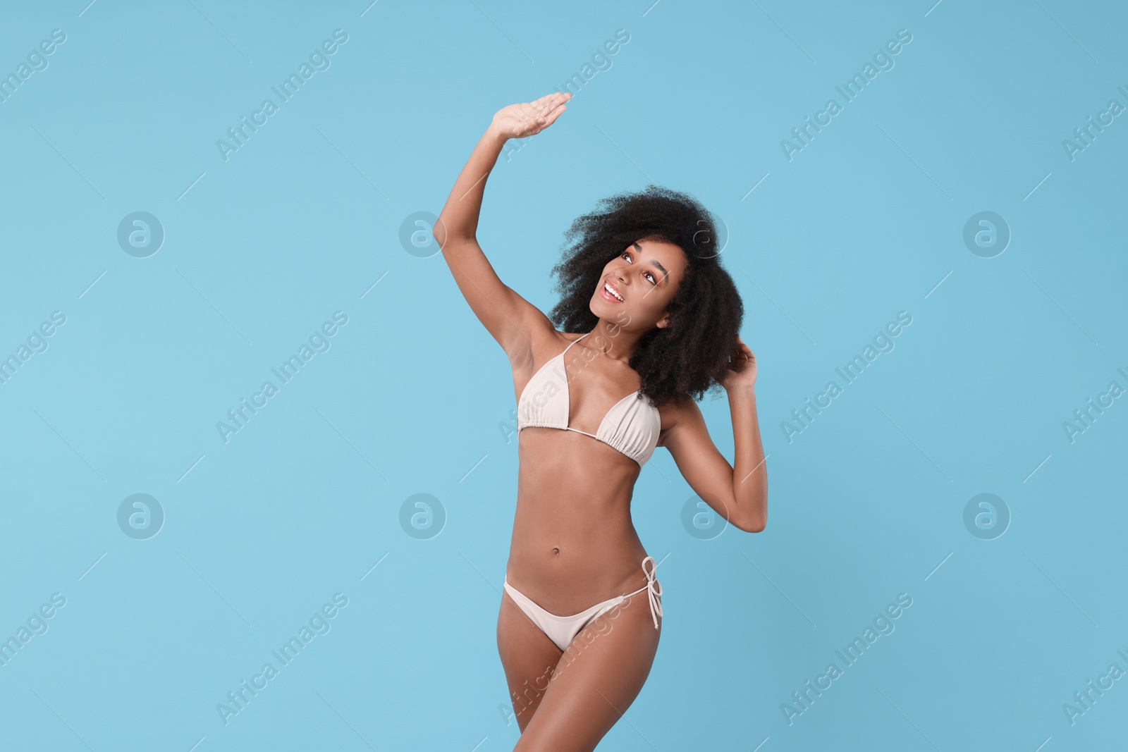 Photo of Beautiful woman in stylish bikini posing on light blue background