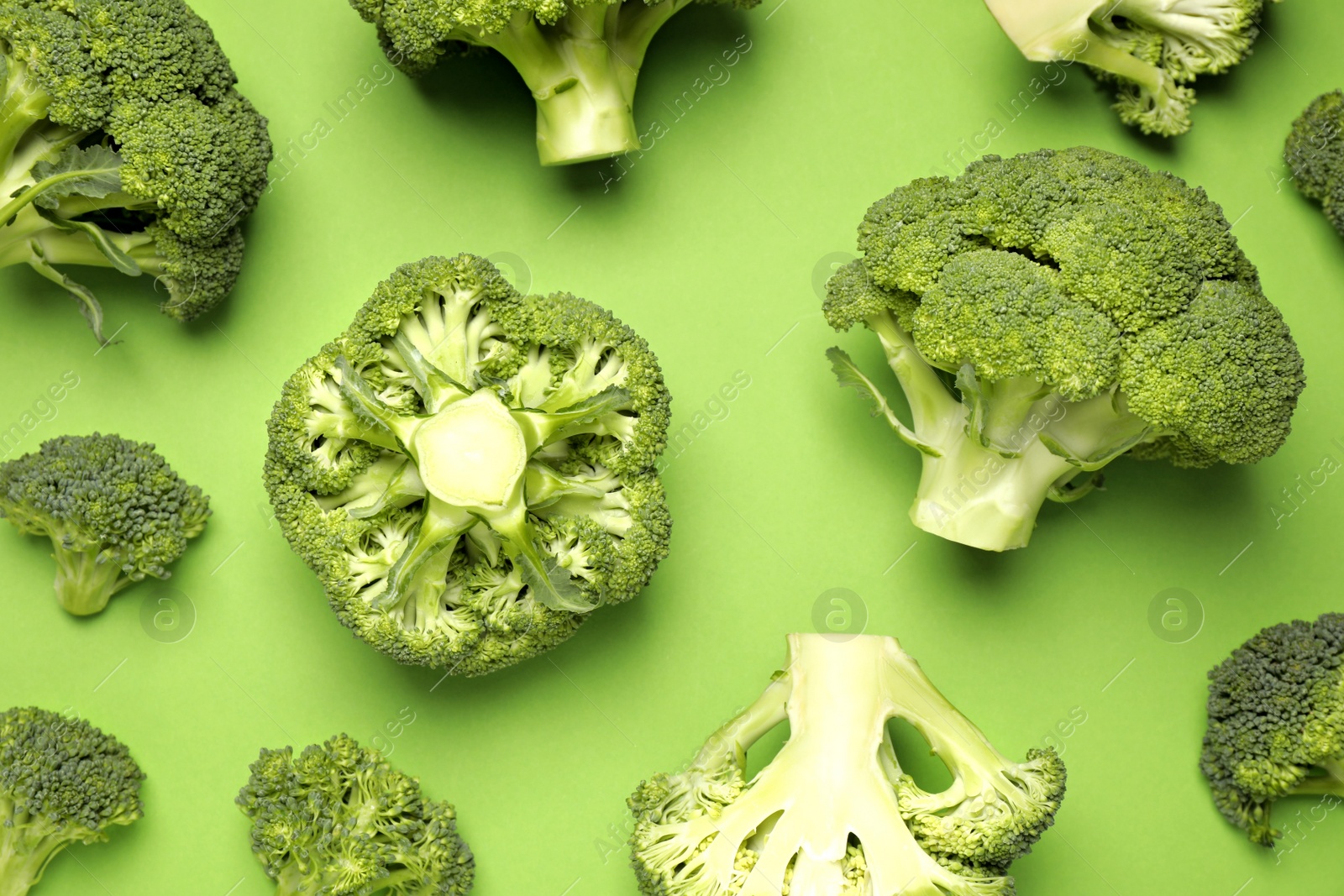 Photo of Fresh broccoli on green background, flat lay