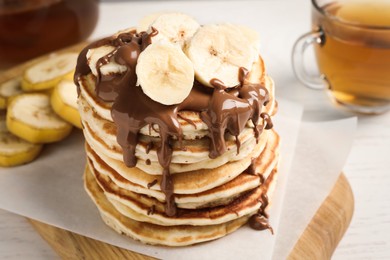 Photo of Tasty pancakes with sliced banana served on white table, closeup