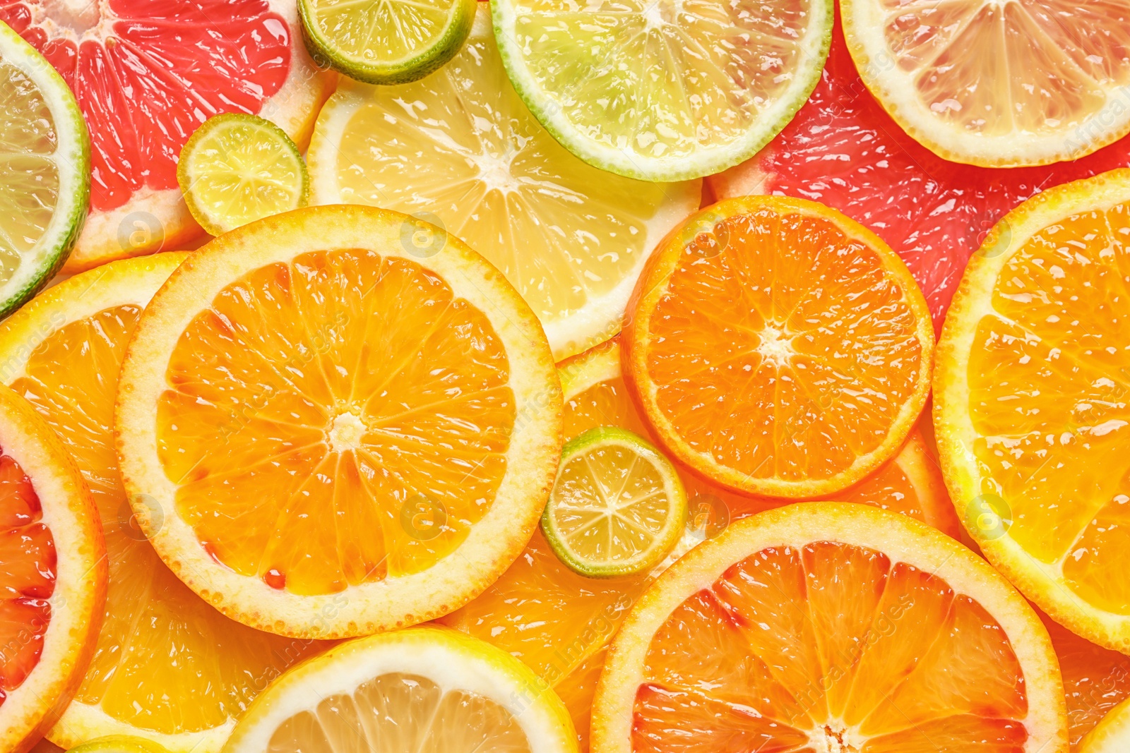 Photo of Slices of fresh citrus fruits as background, top view