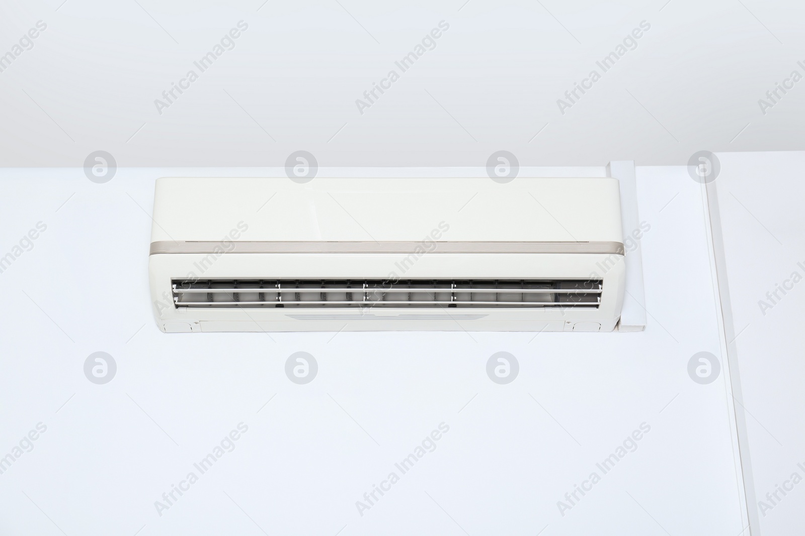 Photo of Modern air conditioner on white wall indoors