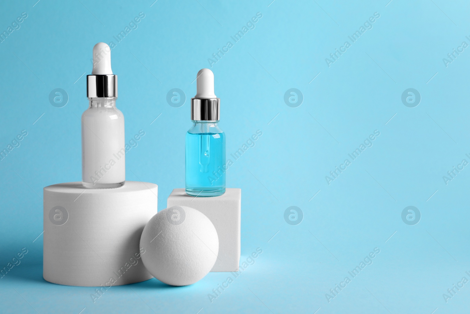 Photo of Stylish presentation of cosmetic serum on light blue background, space for text