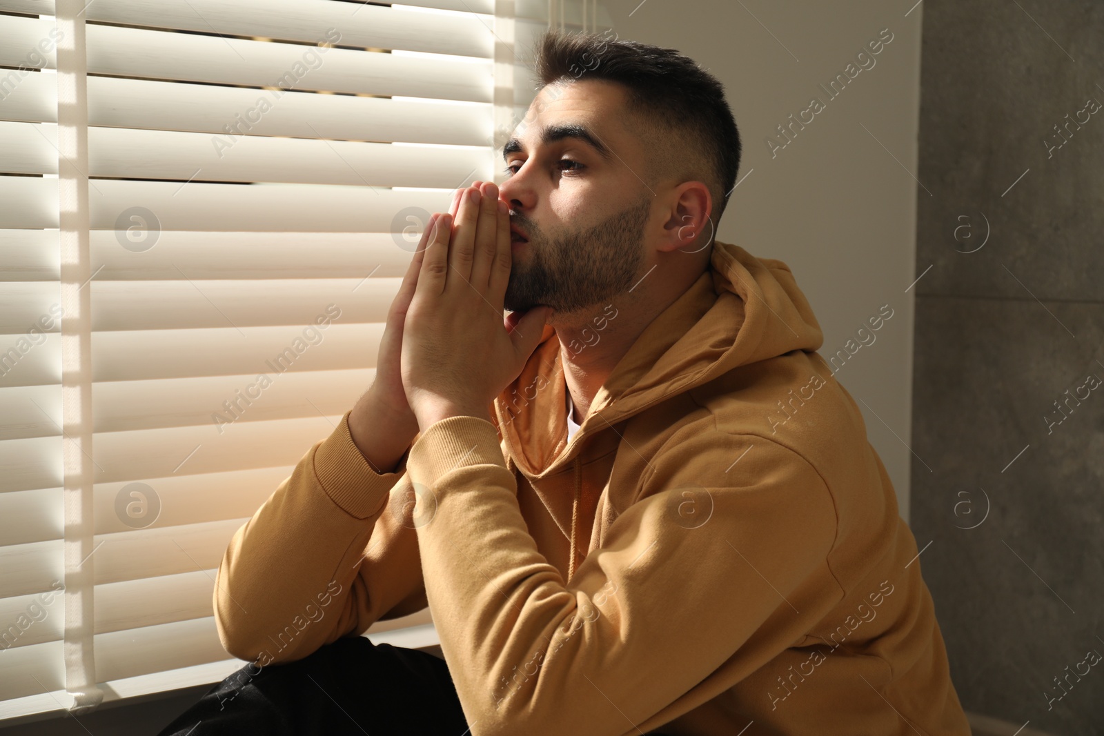 Photo of Sad young man and sitting near window