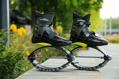 Stylish kangoo jumping boots on wooden bench outdoors