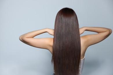 Photo of Young woman with healthy strong hair on light gray background, back view