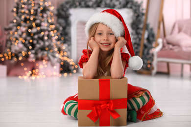 Photo of Cute little child with Christmas gift at home