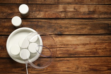 Modern yogurt maker with jars on wooden table, flat lay. Space for text