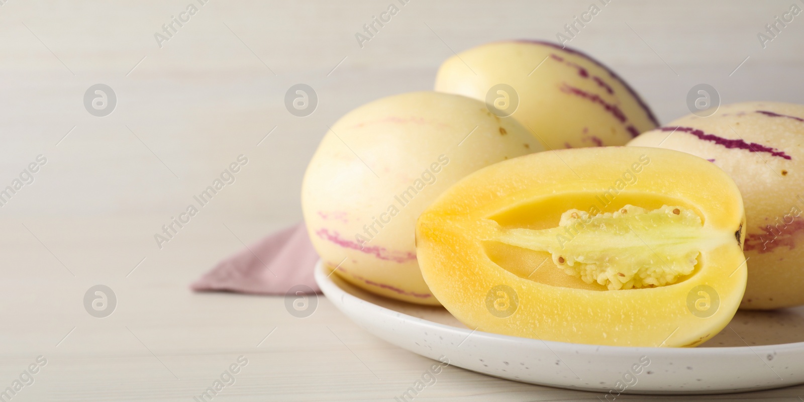Image of Fresh ripe pepino melons on white wooden table, closeup view with space for text. Banner design