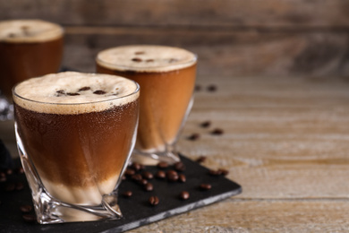 Photo of Glasses of tasty cocktail with coffee beans on wooden table. Space for text