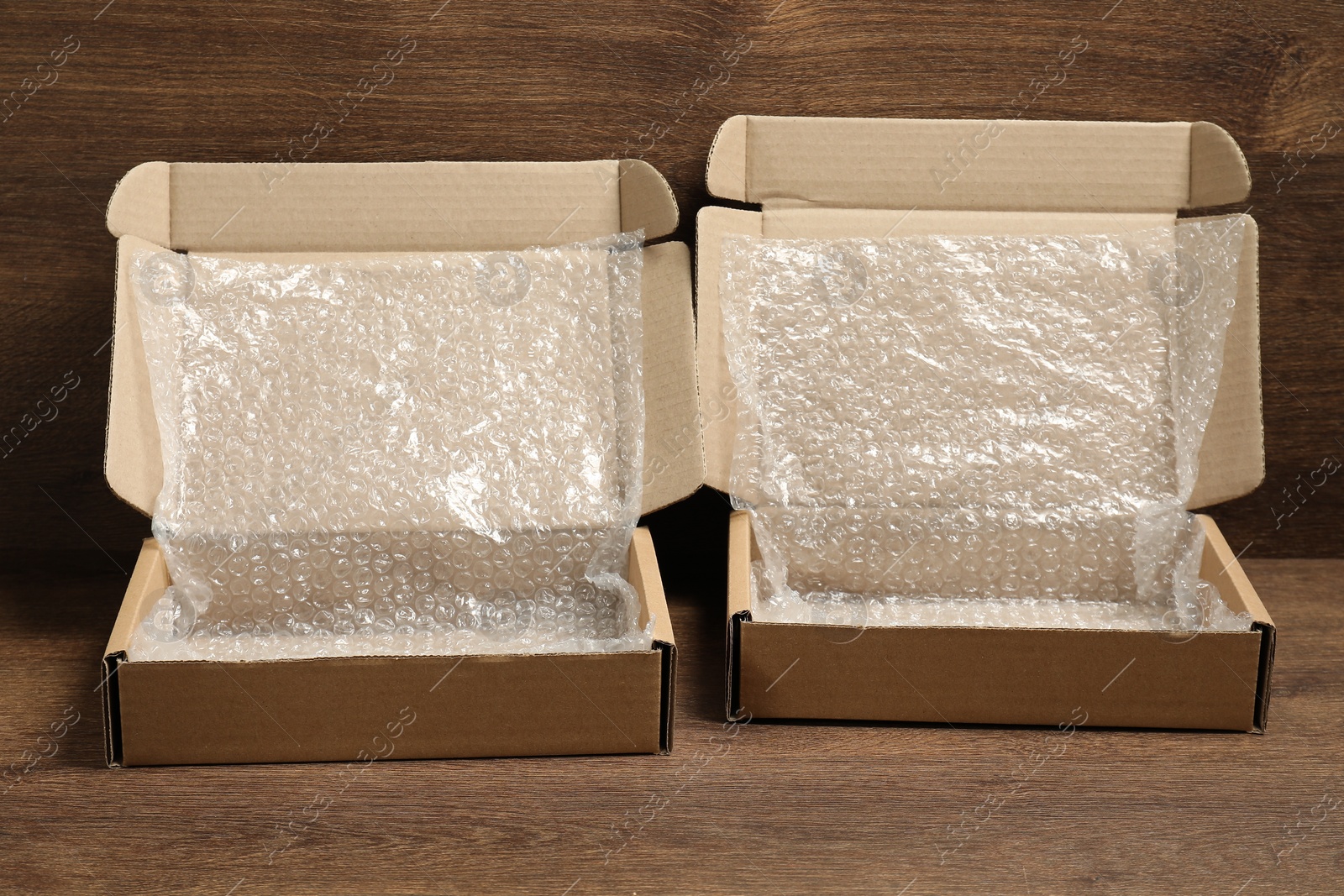 Photo of Open cardboard boxes with bubble wrap on wooden table