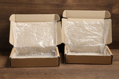 Open cardboard boxes with bubble wrap on wooden table