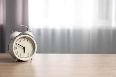 Photo of White alarm clock on wooden table indoors, space for text