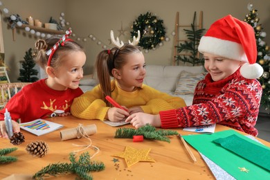 Cute little children making beautiful Christmas greeting cards at home