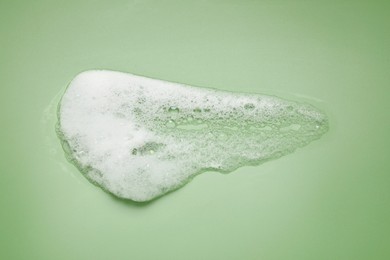 Photo of Smudge of white washing foam on olive background, top view