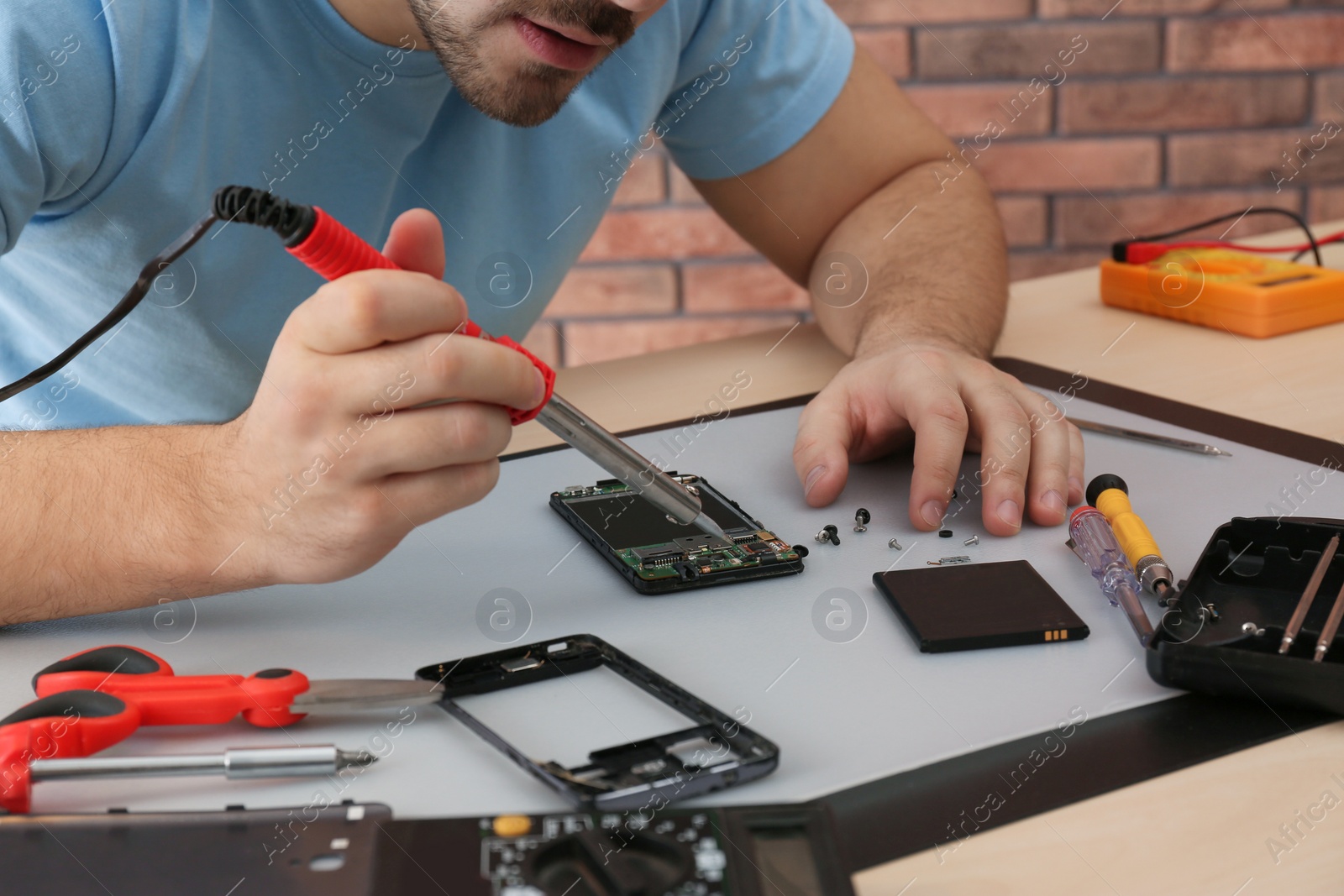 Photo of Technician repairing broken smartphone at table, closeup