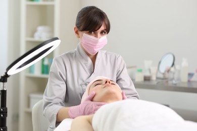Photo of Cosmetologist making face massage to client in clinic