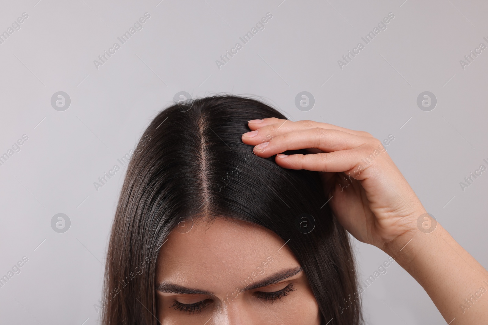 Photo of Woman examining her hair and scalp on grey background, closeup