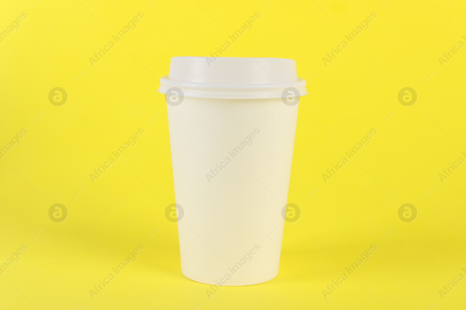 Photo of Paper cup with plastic lid on yellow background. Coffee to go