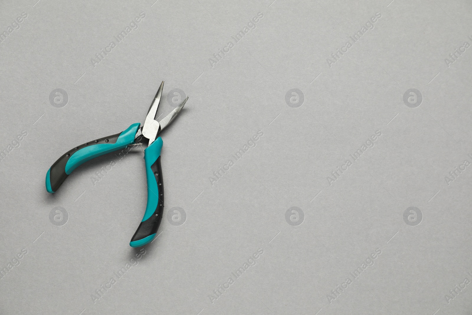 Photo of Bent nose pliers on grey background, top view. Space for text