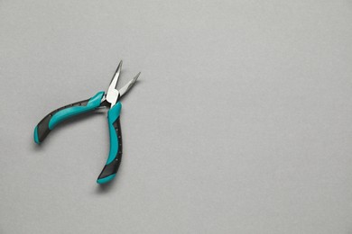 Photo of Bent nose pliers on grey background, top view. Space for text